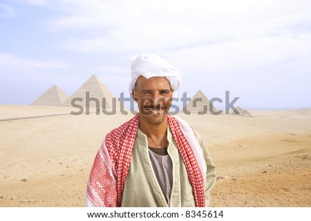 Egyptian man in authentic dress with Pyramids of Giza in background near Cairo, Egypt.