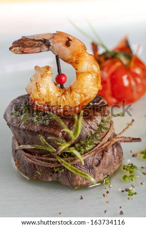 Delicious juicy barbecued steak and prawns with grilled tomato. Surf and Turf style.