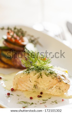 Cooked salmon fillets with dill sauce on white plate