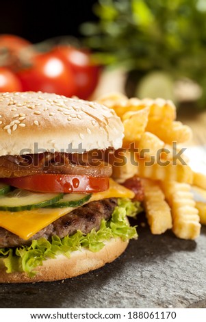 cheeseburger with lettuce, onions, tomato and pickles on a sesame seed bun