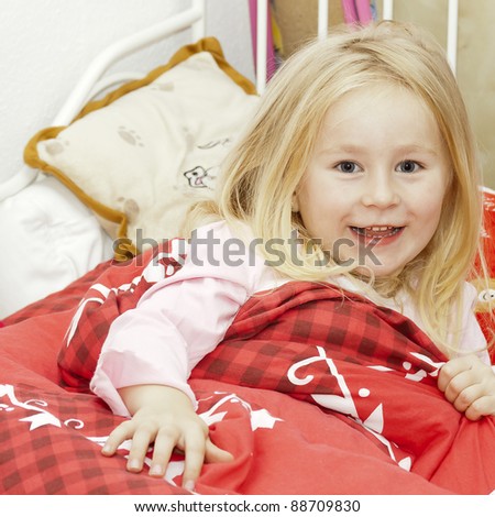 happy little blonde girl under red blanket in bed See my portfolio for more