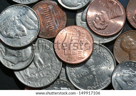 United States change (Penny, Nickel, Dime, & Quarter) scattered about on a black glass background.