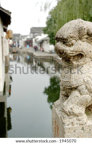 The lion stone sculpture with the back drop of a Chinese town. More with keyword Series11B
