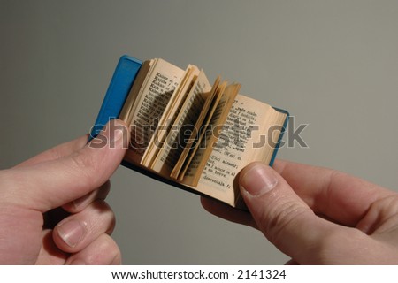 a mini book on hand over faded background