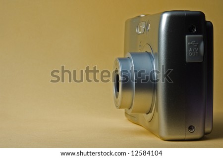Digital photo camera on beige background
