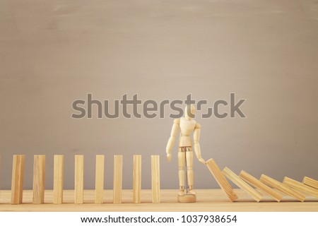 A wooden dummy stopping the domino effect. retro style image executive and risk control concept