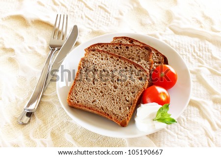 slices of bread with spread cheese, decorated with a cherry tomato and herbs, on a white plate
