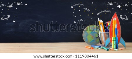 Back to school concept. rocket, earth globe and pencils in front of classroom blackboard