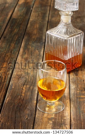 Glass and bottle of liquor like scotch, bourbon, whiskey or brandy on wooden table