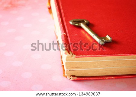 red vintage book with golden classic key on cover . retro pink polka dots background.