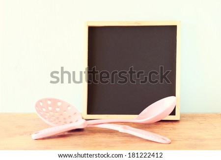 Blackboard on wooden surface and serving spoons. vintage effect process