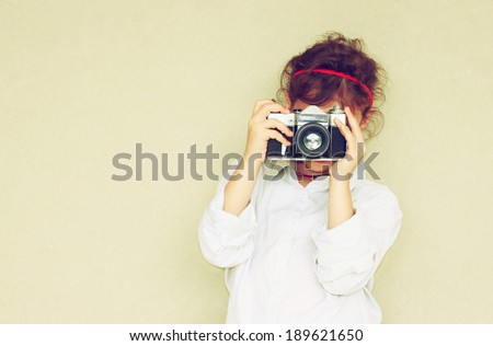 Cheerful kid holding old camera. retro filter room for text.