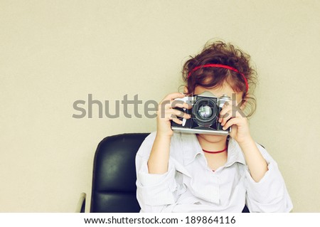 Cheerful kid holding old camera. retro filter room for text.