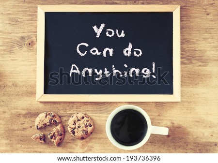 blackboard with the phrase you can do anything over wooden background with cup of coffee and cookies