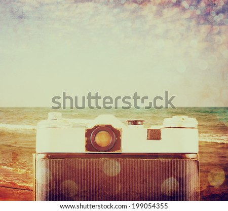 back view of old camera in front sea. vintage filtered image.