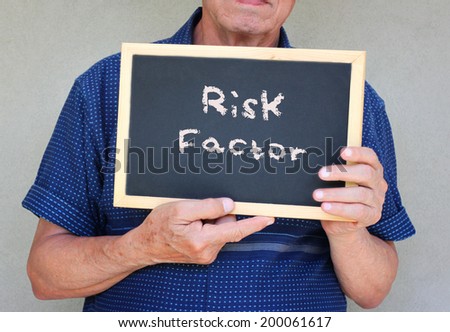 senior man holding blackboard with the phrase risk factor written on it