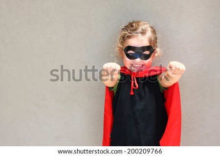 Superhero kid against textured wall background. photographed outdoors under natural light