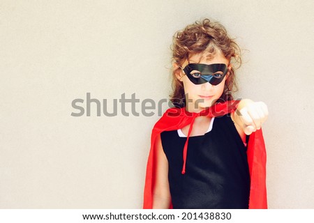 Superhero kid against textured wall background. photographed outdoors under natural light during playing activity