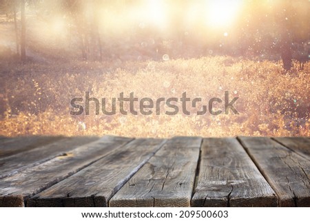 wood board table in front of summer landscape with lens flare.