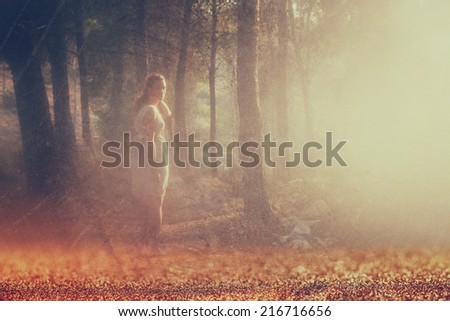 surreal blurred background of young woman stands in forest. abstract and dreamy concept. image is textured and retro toned