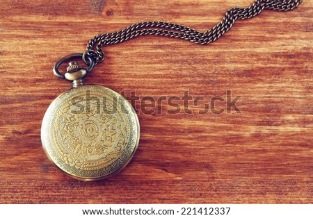 macro image of old vintage pocket watch on wooden table. top view. retro filtered image