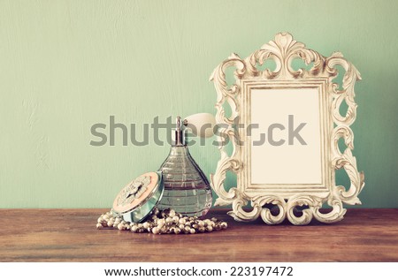 Vintage antique perfume bottles with old picture frame, on wooden table. retro filtered image