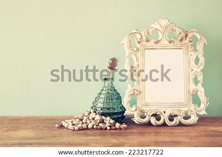 vintage antique perfume bottles with old picture frame, on wooden table. retro filtered image
