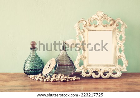 vintage antique perfume bottles with old picture frame, on wooden table. retro filtered image