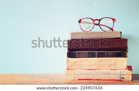 Old books with vintage glasses on a wooden table. retro filtered image