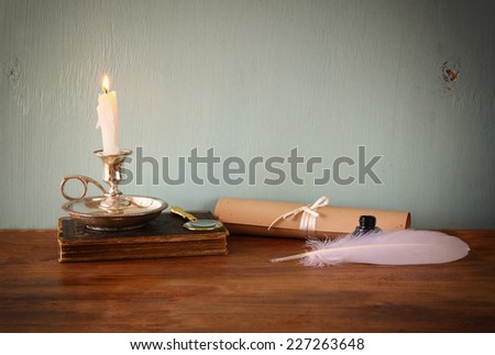 low key image of white Feather, inkwell, scroll ancient book on old wooden table