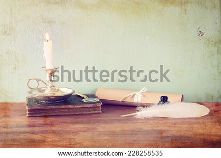 low key image of white Feather, inkwell and diploma on old wooden table. image textured
