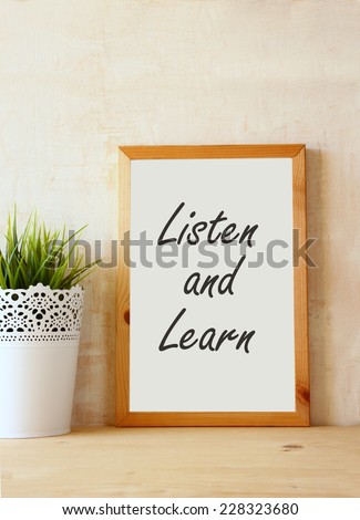 the phrase listen and learn written over white drawing board against rustic textured wall