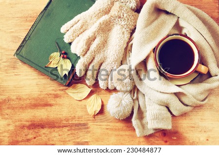 Top view of Cup of black coffee with autumn leaves, a warm scarf and old book on wooden background. filreted image