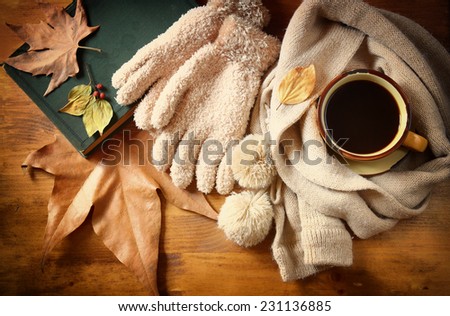 Top view of Cup of black coffee with autumn leaves, a warm scarf and old book on wooden background
