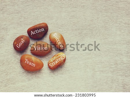 river stones with text over wooden background. strategy, success , goal, team concept