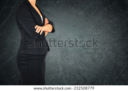 Close up of businesswoman with arms crossed against dark textured background