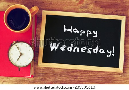 blackboard over wooden table with cup of coffee and and the phrase it's happy wednesday