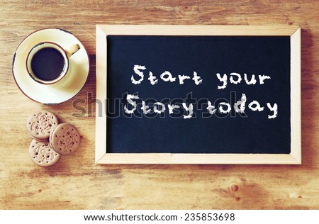 top view of blackboard with the phrase start your story today next to cup of black coffee and cookies