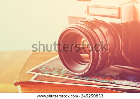 close up photo of old camera lens over wooden table. image is retro filtered. selective focus