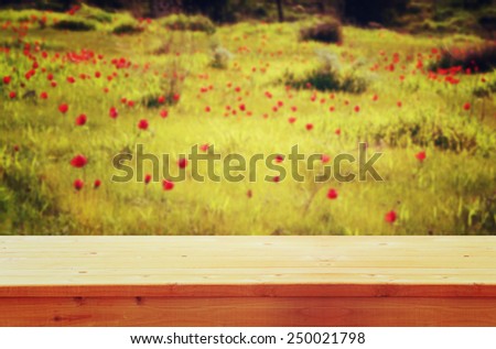 wood board table in front of summer landscape of field with many flowers . background is blurred