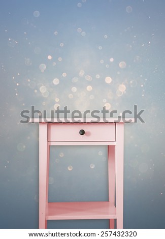 Vintage pink wooden chest drawer near vintage  dreamy blue glitter background