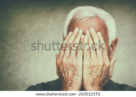 portrait of senior man covering his face with his hands. retro filtered image