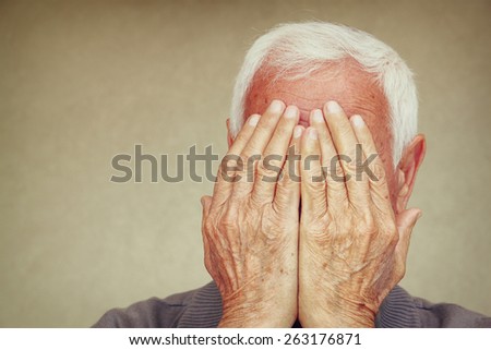 portrait of senior man covering his face with his hands