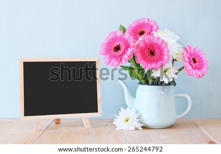 summer bouquet of flowers on the wooden table and blackboard with room for text with mint background. vintage filtered image
