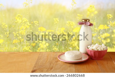 image of greek cheese , bulgarian cheese and milk on wooden table over floral abstract background. Symbols of jewish holiday - Shavuot