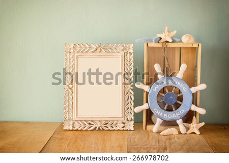 old vintage frame with naurical  wheel on wooden table. vintage filtered image