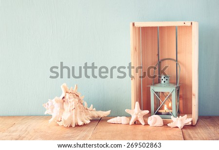 sea shells and lantern on wooden table. vintage filtered image