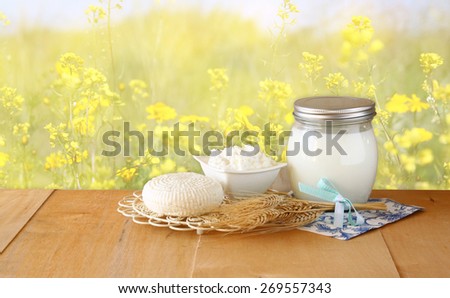 image of greek cheese , bulgarian cheese and milk on wooden table over floral abstract background. Symbols of jewish holiday - Shavuot