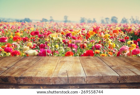 vintage wooden board table in front of summer flowers field bloom landscape with lens flare.