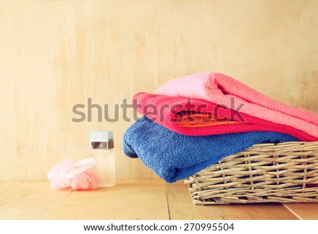 towel in wicker basket over wooden table and textured background. image is retro style filtered